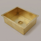 Rectangular brass undermount sink with hammered flange and brass basket strainer on a plain background