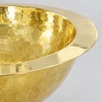 Close-up of the hammered round brass undermount bathroom sink showing the finish