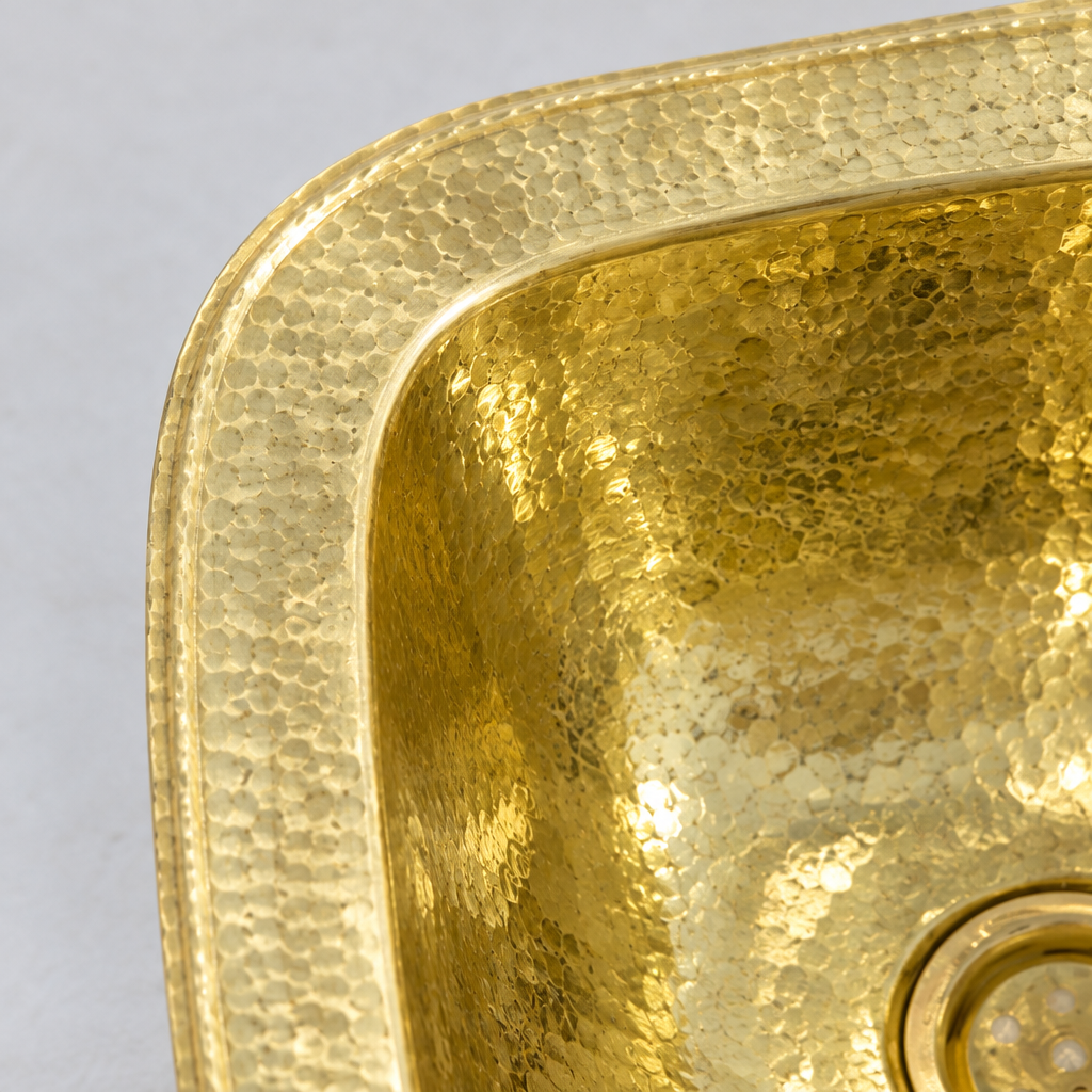 Close-up of the hammered square brass drop-in sink with overflow showing the finish