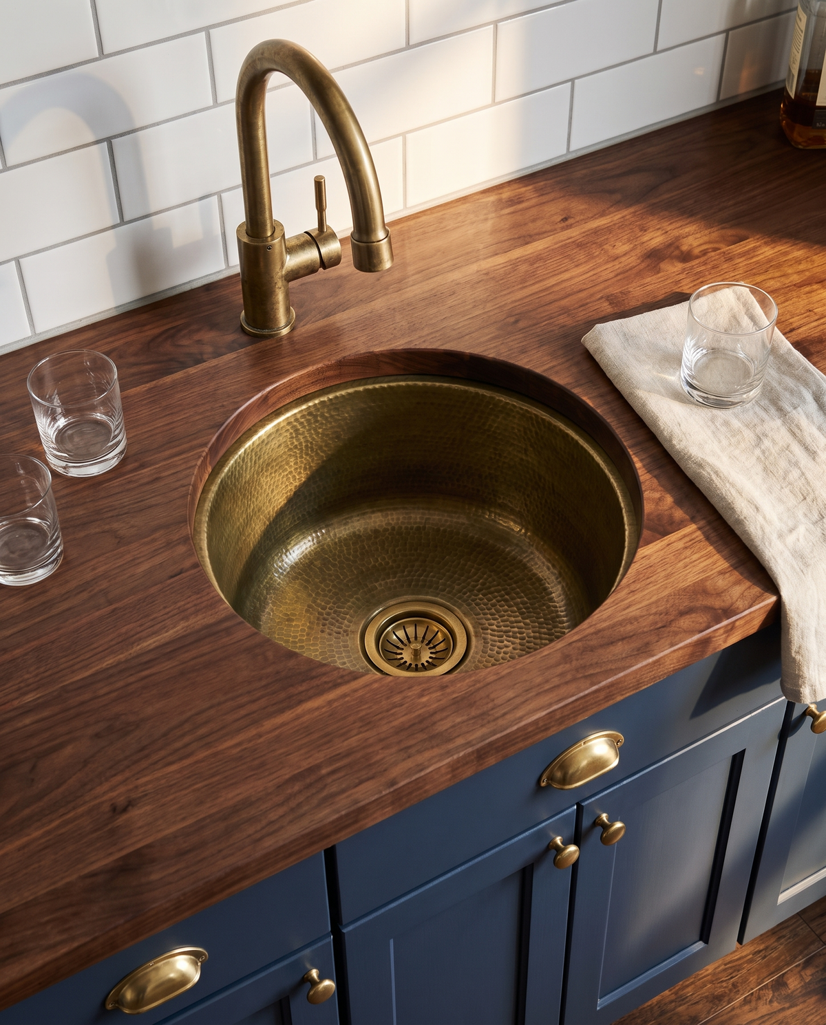Hand-hammered unlacquered brass bar sink installed undermount in a walnut butcher block counter in an American home wet bar