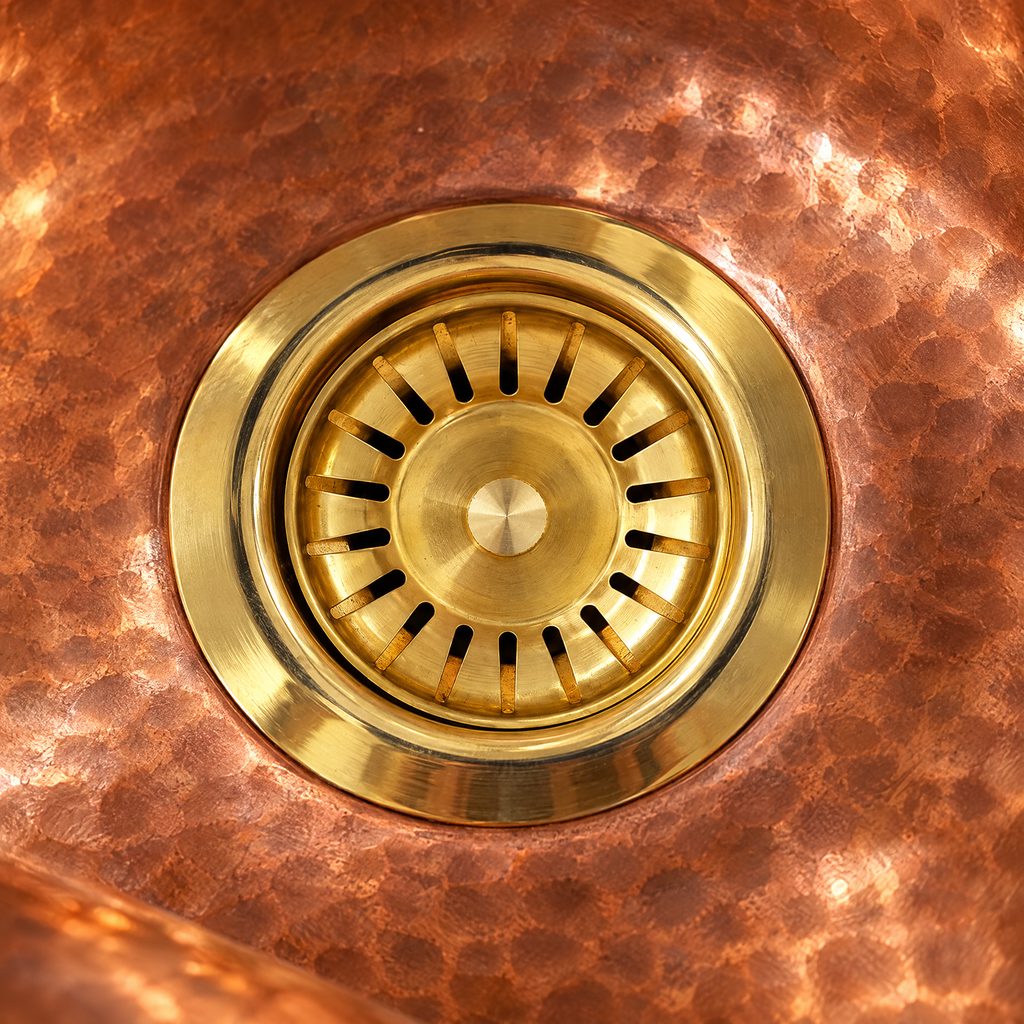 Close-up of a brass sink strainer flange in a hammered copper basin