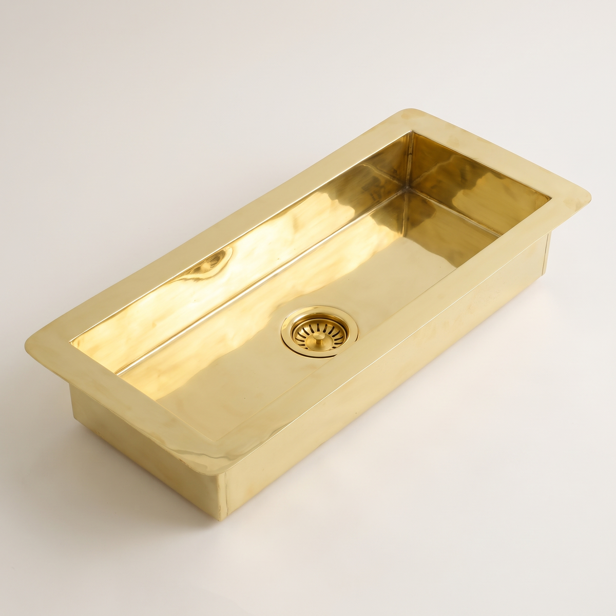 Narrow rectangular brass undermount sink with flat flange and brass basket strainer