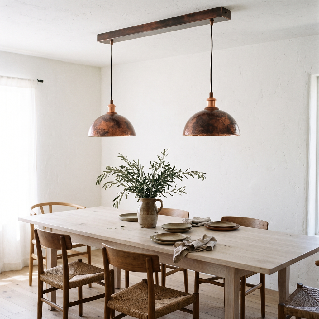 Pair of oxidized copper dome pendants over a long white oak dining table