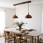Pair of oxidized copper dome pendants over a long white oak dining table