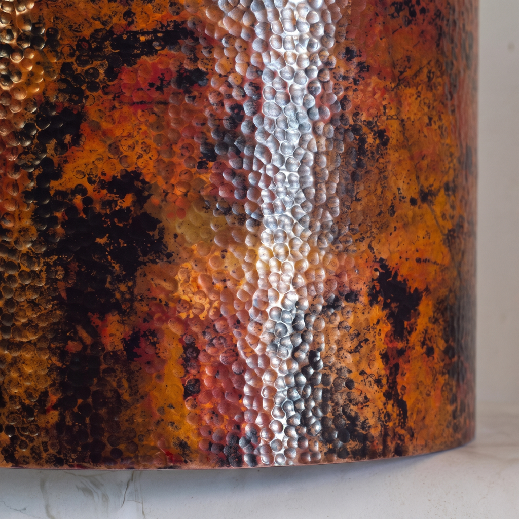 Close-up of the hammered copper drum showing the oxidized patina and silvery seam band