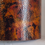 Close-up of the hammered copper drum showing the oxidized patina and silvery seam band
