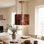 Oxidized copper drum pendant light above a white oak dining table