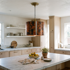 Oxidized hammered copper drum pendant light over a white marble kitchen island