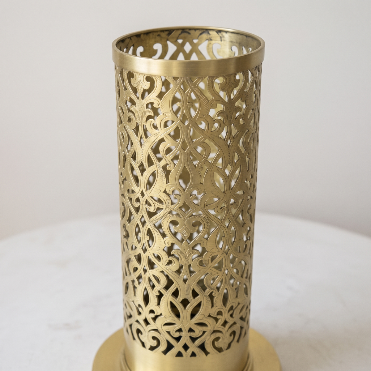 Close-up of the hand-pierced arabesque pattern on the brushed brass cylinder
