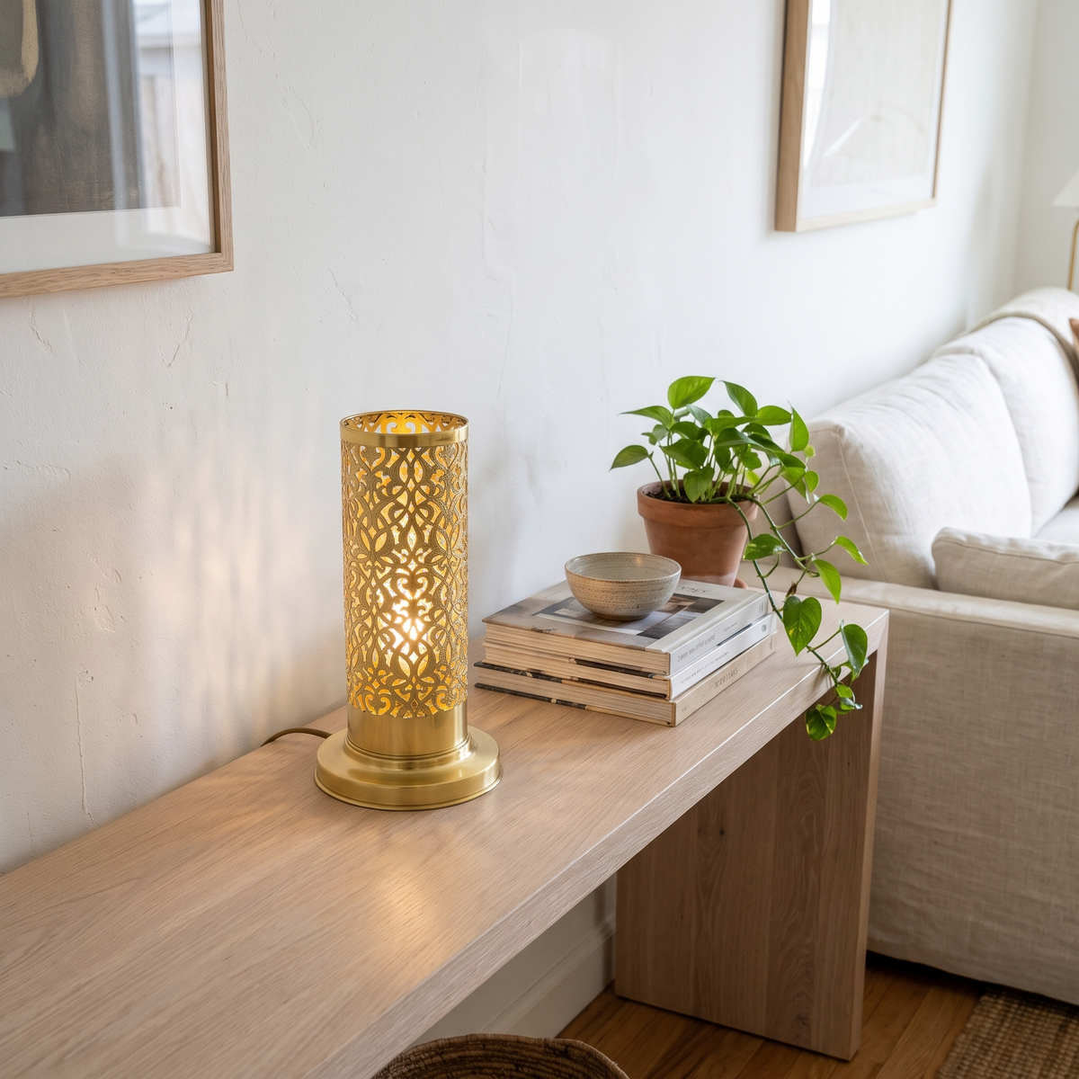 Unlacquered brass pierced cylinder lamp on a white oak console in a living room