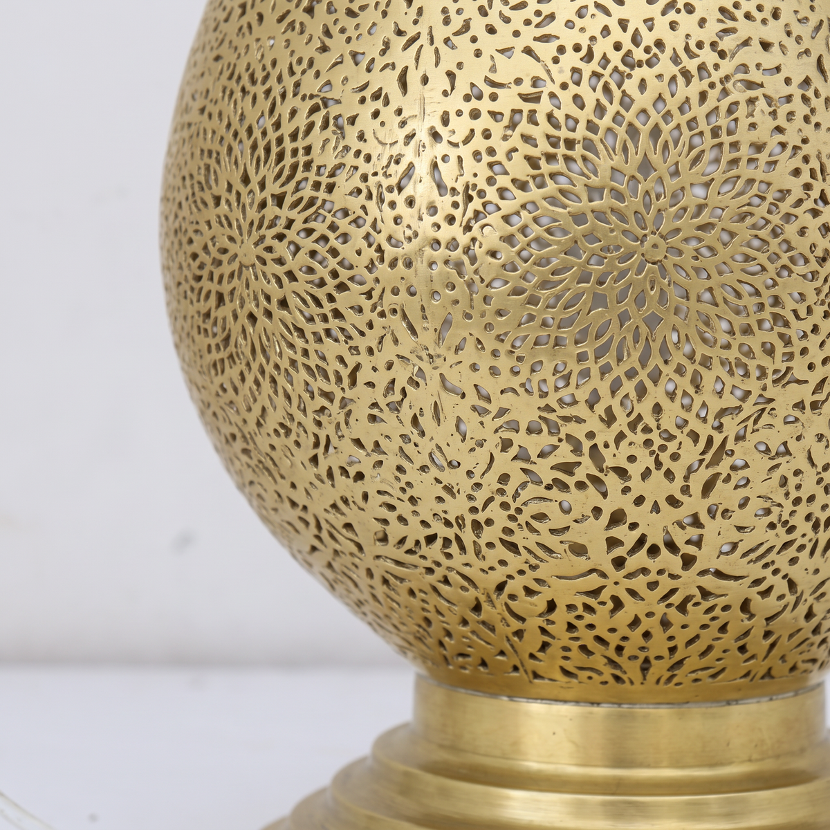 Close-up of the hand-pierced Moroccan filigree on the unlacquered brass teardrop lamp