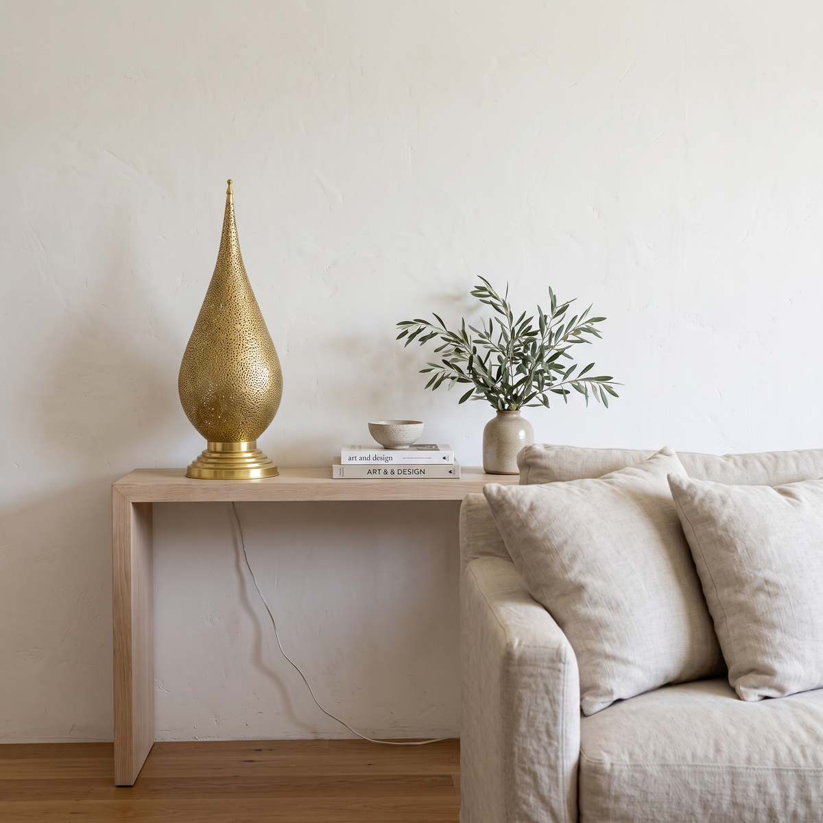 Unlacquered brass teardrop table lamp on a white oak console in a bright living room