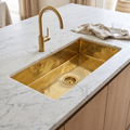 Narrow brass undermount prep sink with brass basket strainer in a marble kitchen island