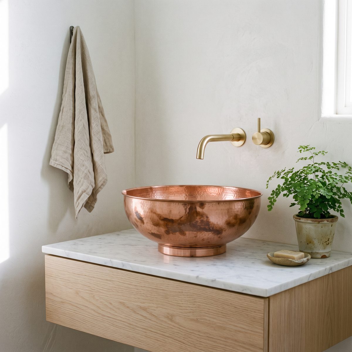 Copper bowl vessel sink on a floating white oak vanity in a bright powder room