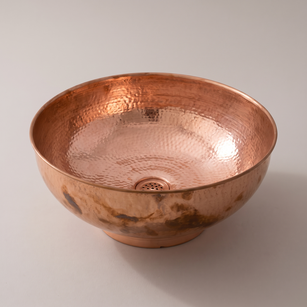 Round copper vessel bowl with rolled rim, foot ring and hammered interior on a plain background