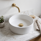 Solid brass push-up drain installed in a white vessel sink on a marble vanity