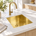 Square brass undermount sink in a sunlit white marble kitchen island