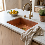 Copper prep sink with brass basket strainer and brushed brass gooseneck faucet in a white oak kitchen island