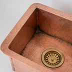 Close-up of hammered copper flange, inside corner and brass basket strainer drain