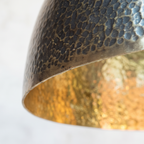 Two-tone rim of the hammered brass dome pendant: dark patina outside, bright brass inside