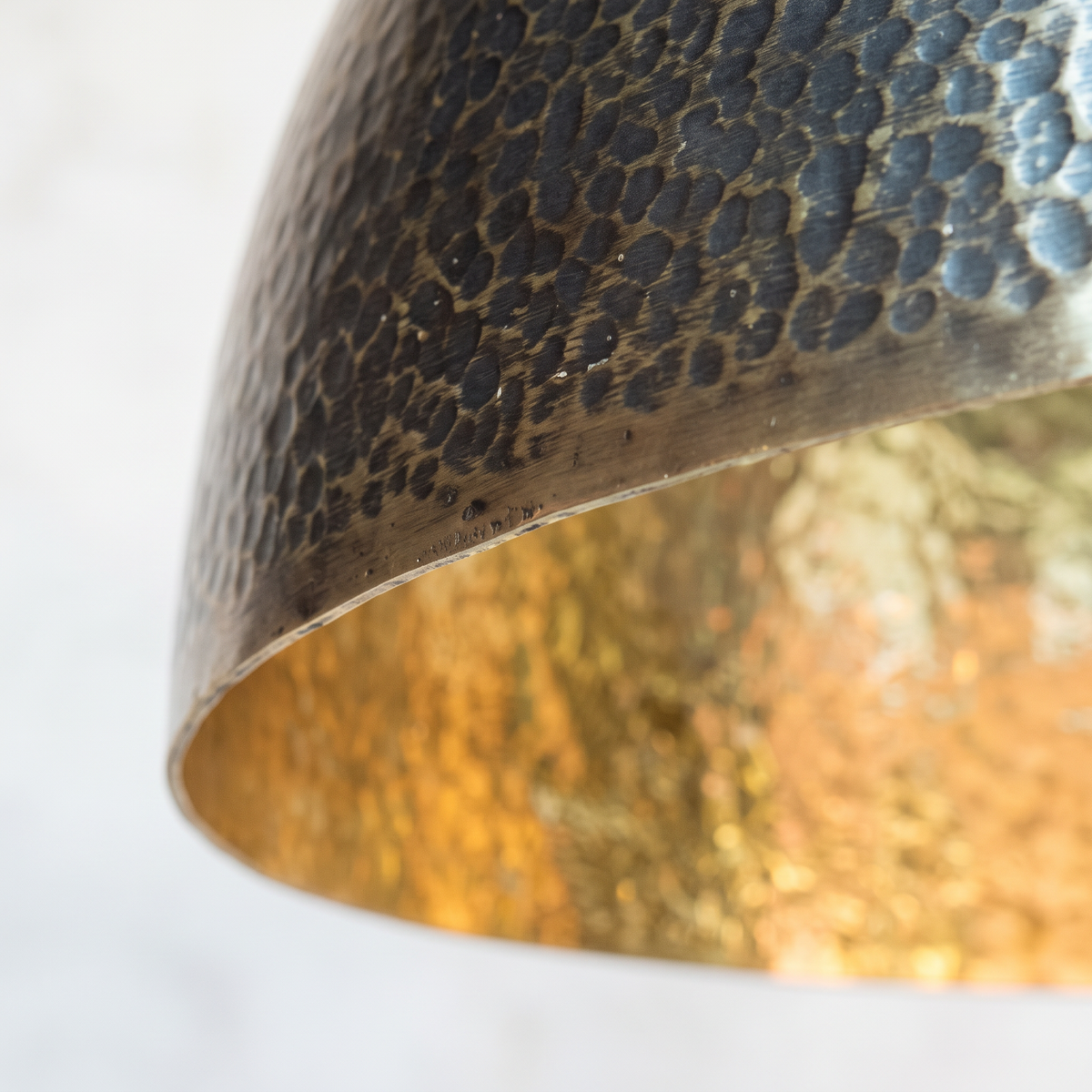 Two-tone rim of the hammered brass dome pendant: dark patina outside, bright brass inside