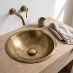 Unlacquered brass push-up drain in a hammered brass drop-in sink on a white oak vanity