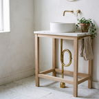 Brass floor-mounted S-trap under an oak console sink on a marble floor