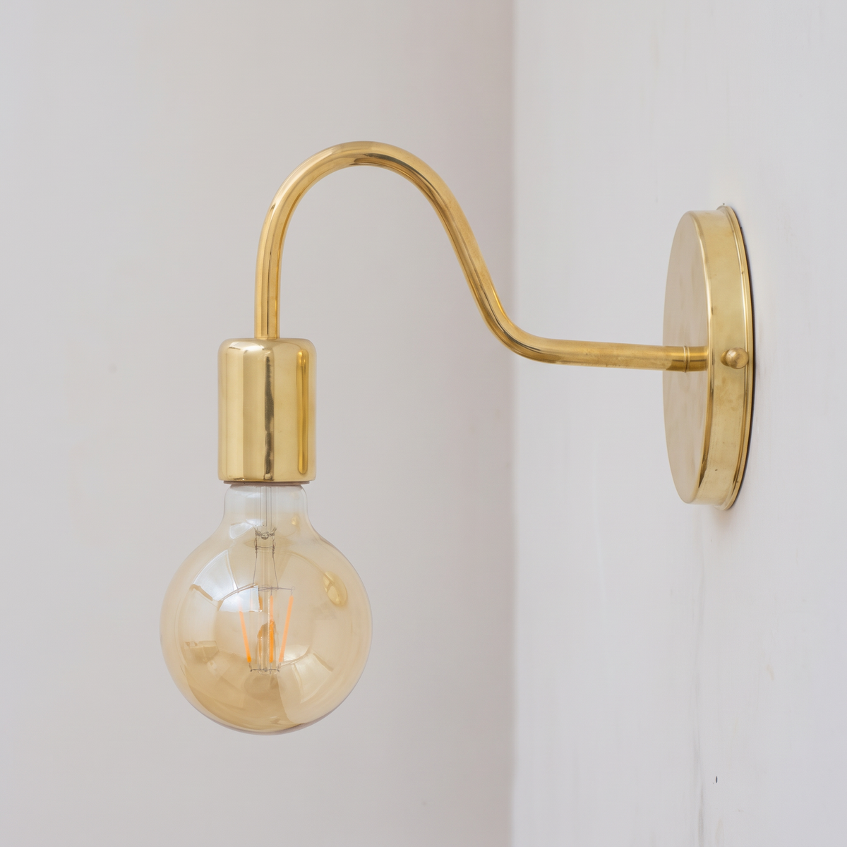 Unlacquered brass gooseneck wall sconce with bare globe bulb