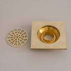 Unlacquered brass square shower drain with round web grate on a light background