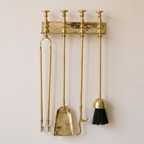 Brass wall rack with tongs, shovel, poker and brush on a light background