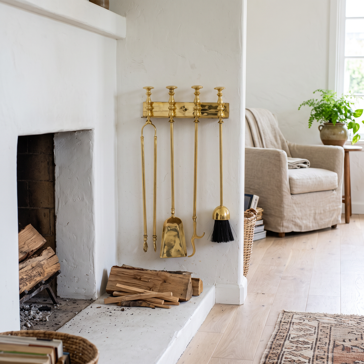 Wall-mounted polished brass fireplace tools beside a white plaster fireplace in a living room